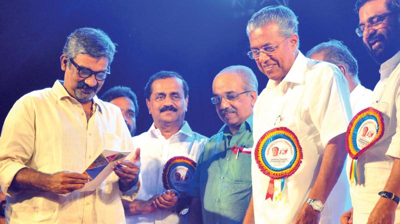 Film director Ranjith takes a look at states progress report after receiving the first copy from Chief Minister Pinarayi Vijayan in Kozhikode on Monday. (Photo: DC)