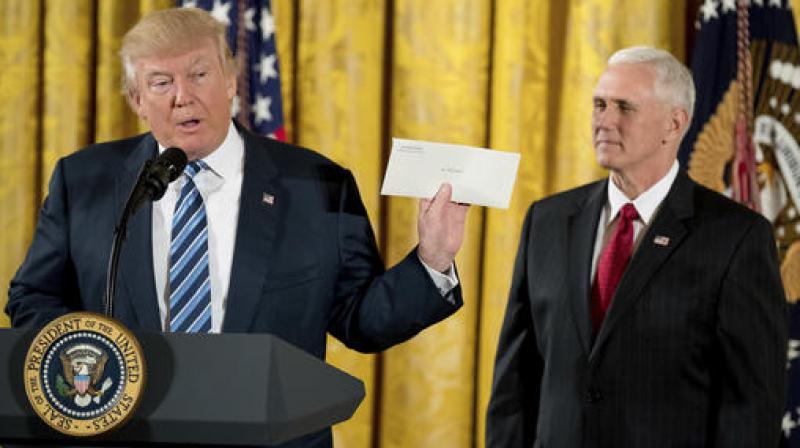 President Donald Trump, accompanied by Vice President Mike Pence holds up a letter left for him by former President Barack Obama as he speaks at a White House senior staff swearing in ceremony in the East Room of the White House in Washington. (Photo: AP)