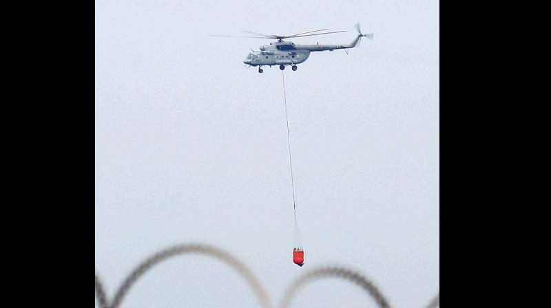 An Air Force helicopter  carries water to douse the raging ire at Mukkunnimala