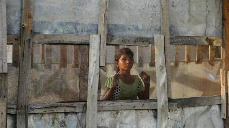 In this August 16, 2017 photo, a Rohingya refugee girl looks through a mesh window at a camp set up for the refugees on the outskirts of Jammu. (Photo: AP)