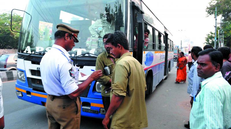 A cop issues a challan to a RTC driver in the city.