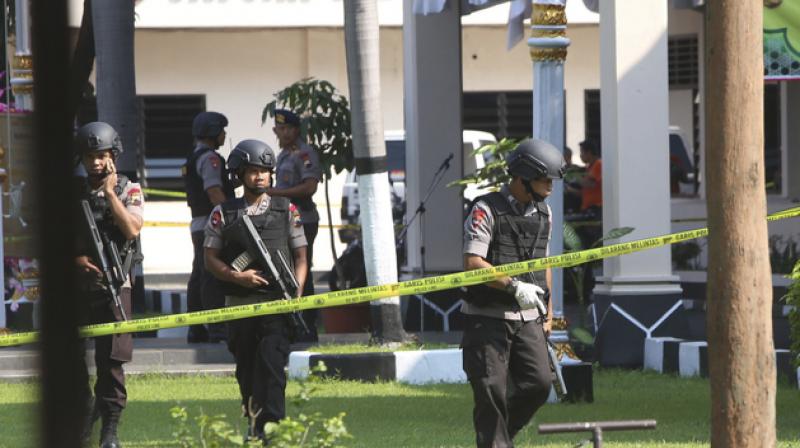 Members of police bomb squad examine the surrounding area near where a suicide bomber blew himself up at the local police headquarters in Solo, Central Java, Indonesia. (Photo: AP)