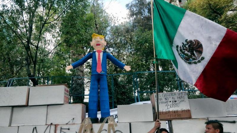 People protest against US President Donald Trumps inauguration next to a fake wall with a Mexican national flag and a dummy representing him in Mexico City.(Photo: AFP)