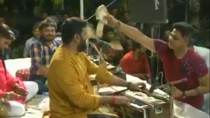 In Thursdays devotional programme, folk singer Brijraj Gadhvi was showered with wads of currency notes in the denominations of Rs 10-500. (Screengrab | ANI)