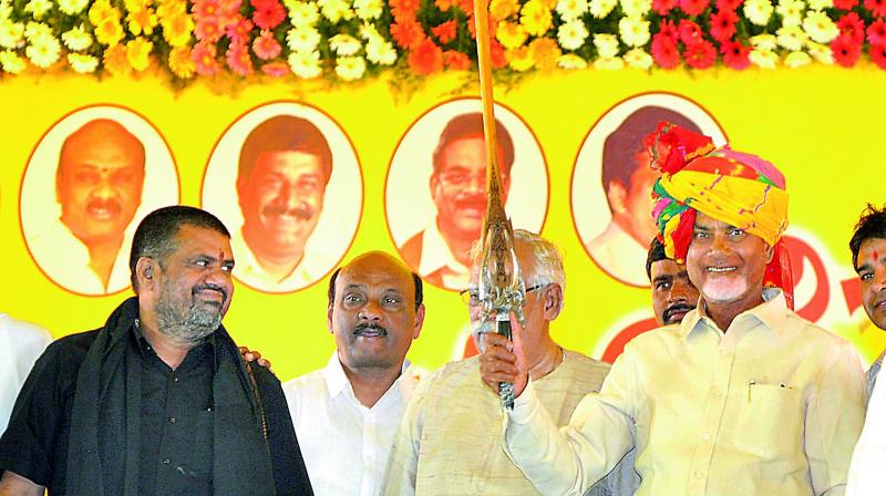 Chief Minister N. Chandrababu Naidu holds a sword presented to him during a felicitation by the TD activists during a public meeting at the AU Engineering College Grounds in Visakhapatnam on Thursday. (Photo: DC)