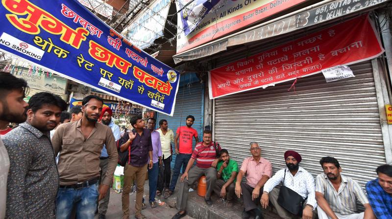 Shopkeepers sitting outside their closed shops of firecrackers at Sadar Bazar in New Delhi on Monday. (Photo: PTI)