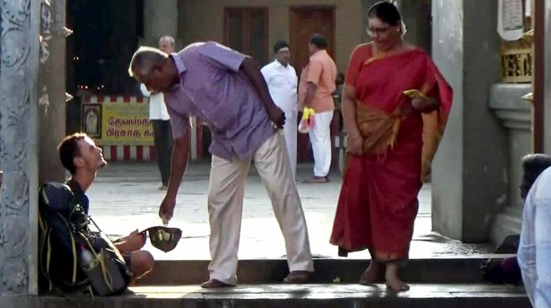 A temple visitor offers money to Evangelin Berngowe at Kumarakottam Murugan temple in Kancheepuram. (Photo: DC)