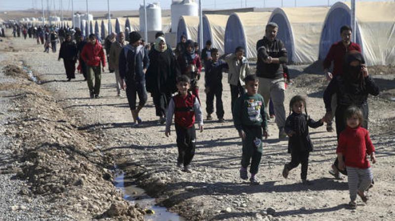Iraqi citizens who fled the fighting between Islamic State militants and the Iraqi forces, walk inside a camp for internally displaced people, in Khazer, east of Mosul, Iraq. (Photo: AP)