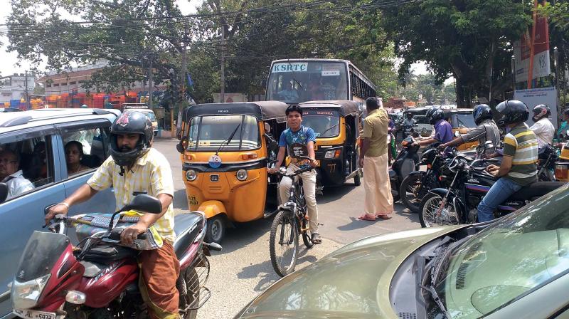 An auto driver at Edappazhinji direct the vehicles in an effort to clear the jam at the junction on Thursday.