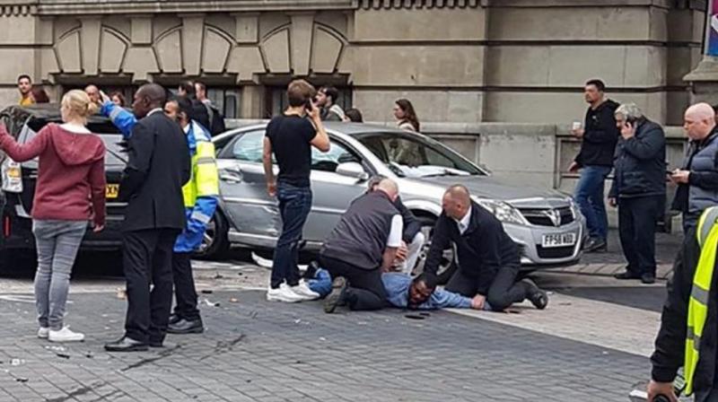 A handout picture obtained from the twitter user @StefanoSutter shows a man being restrained alongside vehicles (centre R) on Exhibition Road, in between the Victoria and Albert museum and the Natural History Museum, in London on October 7, 2017. (Photo: AFP)