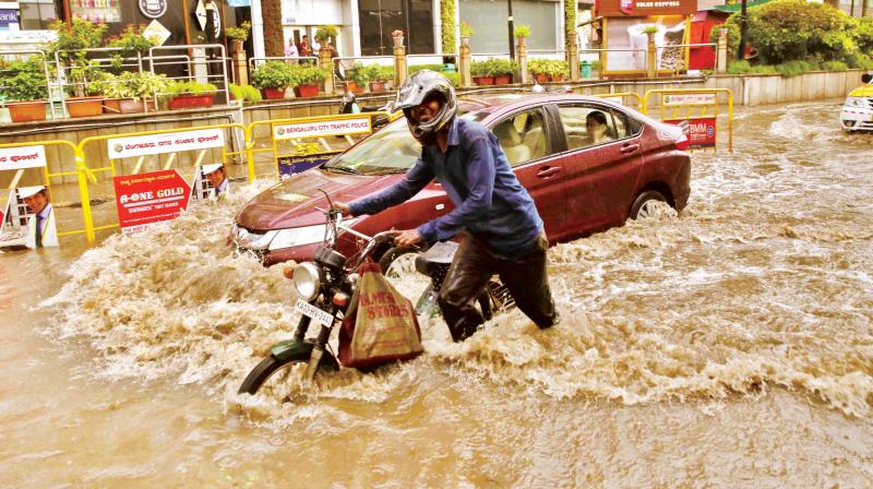 Vehicles struggle through waterlogged roads after a heavy downpour in Bengaluru on Thursday