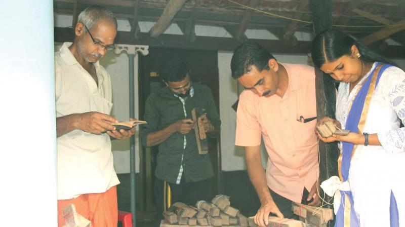 Researchers along with house members look at the ancient palm leaf manuscripts at Varakappilli Illam in Pilakkad near Thrissur.
