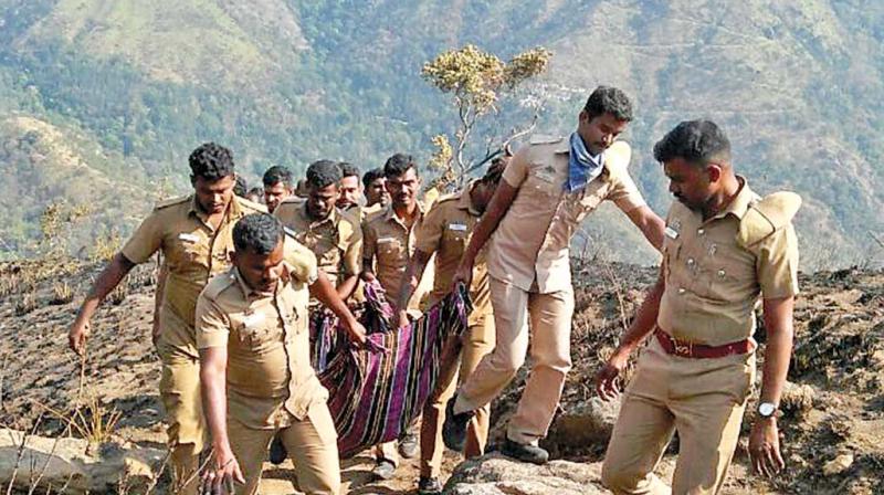 Cops rescue one of the victims from Kurangani forest in Theni on Monday (Photo: DC)