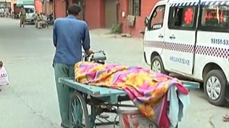 A labourer was compelled to carry his fathers body on a cart as he was unable to pay Rs 400 to a private ambulance carrier. (Photo: Videograb/ANI)