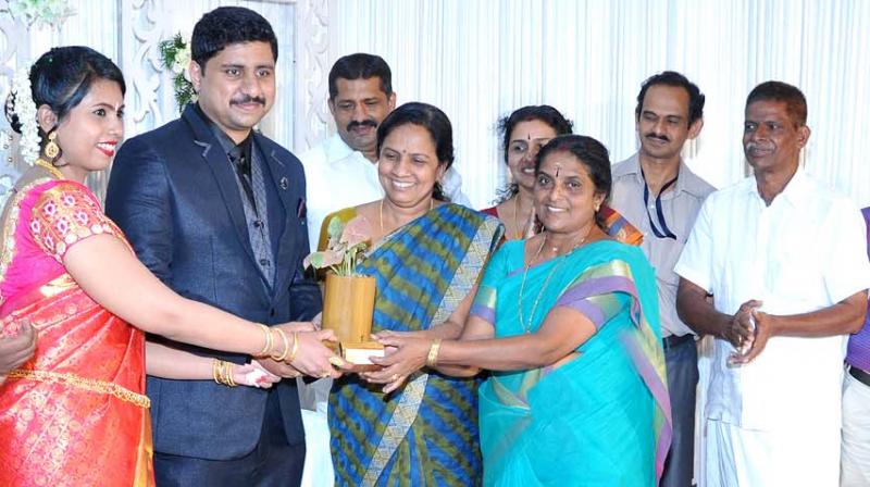 Municipal chairperson Sathi Jayakrishnan and vice-chairperson Nisha Vinayan hand over a gift to the newlyweds.