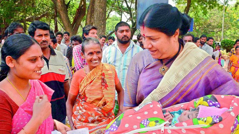 Womens panel chairperson Nannapaneni Rajakumari cradles a newborn during her visit to the Old Government Hospital in Vijayawada on Tuesday. (Photo: DC)