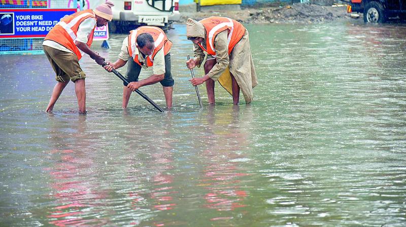 GHMC workers struggle to open a drainage point at a flooded road in Hyderabad on Monday. (Photo: DC)