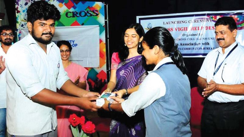 Kozhikode Corporation secretary Mrinmayi Joshi presents the mobile phone to students of Holy Cross College of Management and Technology on Monday. (Photo: DC)