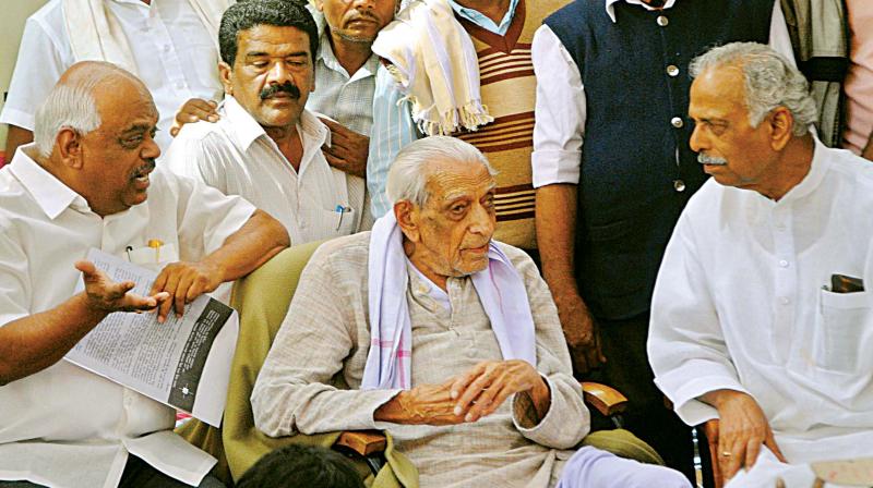 Ministers Ramesh Kumar and Kagodu Thimmappa pacify freedome fighter H.S. Doreswamy who was on a protest demanding that vacant government land be allotted to the landless.