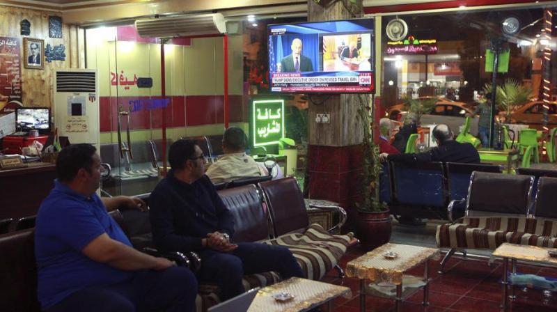 Men at a cafe in Baghdad watch the news on Iraq being removed from the US travel ban. (Photo: AP)
