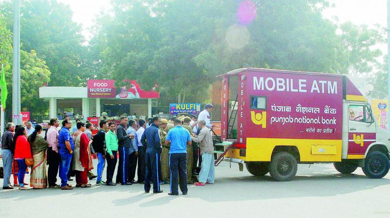 People queue up to withdraw money from a mobile ATM at ITPO, Pragati Maidan in New Delhi on Monday. In an attempt to reduce rush at bank branches and ATMs, banks have pressed into service mobile ATM vans. (Photo: PTI)