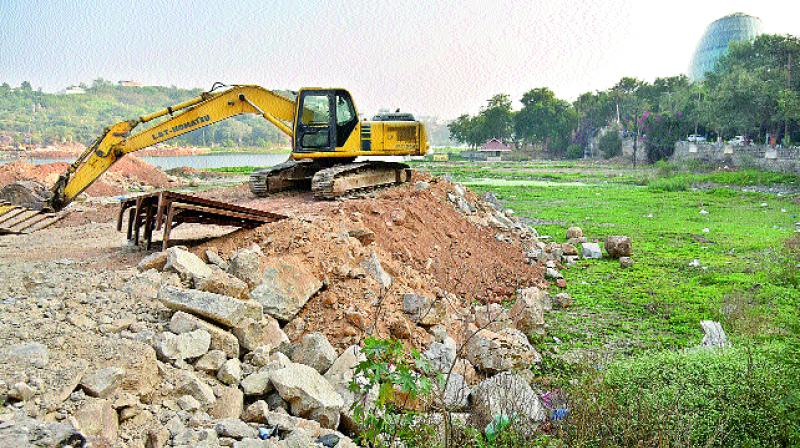 A machine dumps excavated mud and construction material on the banks of the lake. (Photo: DC)