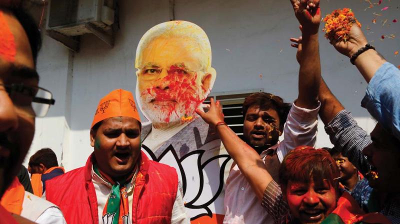 Bharatiya Janata Party supporters raise a cutout of Indian Prime Minister Narendra Modi as they celebrate winning seats in the state of Uttar Pradesh in Lucknow. 	AP FILE PIC