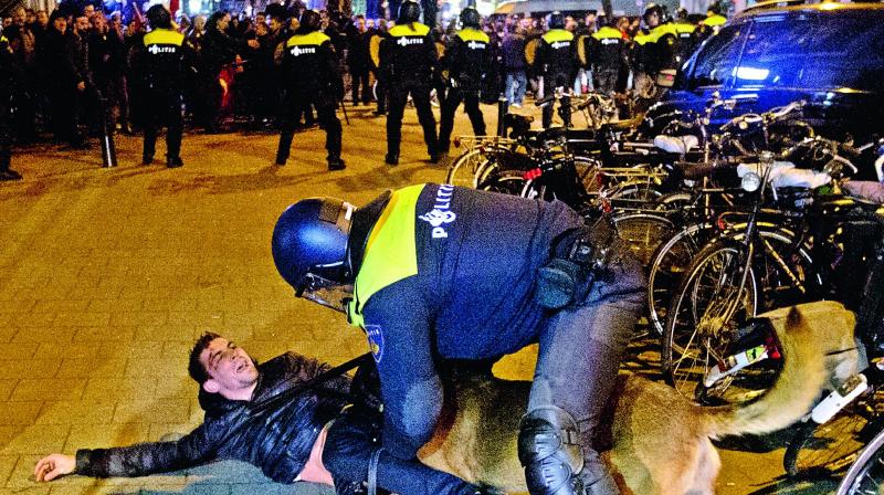 A Dutch riot policeman tries to get his dog to let go of a man after riots broke out during a pro Erdogan demonstration at the Turkish consulate in Rotterdam, Netherlands, on Sunday. 	(Photo: AP)