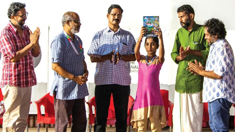 Kochi Muziris Biennale artist P.K. Sadanandan (second from left) after presenting the specially designed book to a student of AMUPS in Malappuram. Also seen are (from right) KBF secretary Riyas Komu, AMUPS teacher Subhash P K, AMUPS headmaster T. Gopalakrishnan and ABC programme head Manu Jose. (Photo: DC)