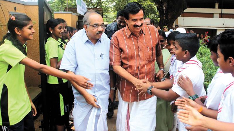 Education minister Prof C. Ravindranath greets students of Medical College Campus High School on Saturday. MLA A. Pradeep Kumar is also seen. (Photo: DC)