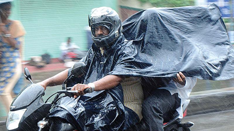 A pillion rider takes protection under a plastic cover from the heavy rain in Kochi city on Monday.  (Photo: ARUN CHANDRABOSE)