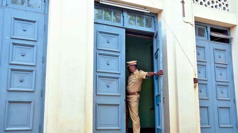 A cop shuts a door of the Madras University Centenary Auditorium on Friday. (Photo: DC)