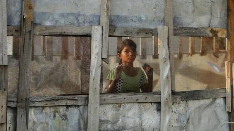 In this August 16, 2017 photo, a Rohingya refugee girl looks through a mesh window at a camp set up for the refugees on the outskirts of Jammu. (Photo: AP)