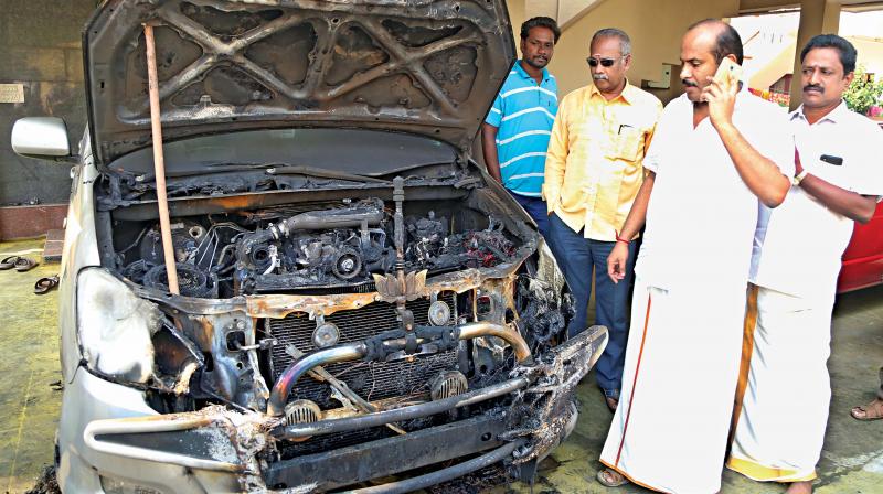 BJP district  president  C. R. Nandhakumar takes a look at his car gutted in fire in Coimbatore on Wednesday. (Photo: DC)