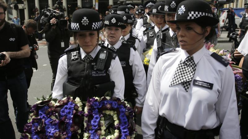 Police officers arrive to lay flowers at the scene of Saturdays attack in the London Bridge area in London. (Photo: AP)