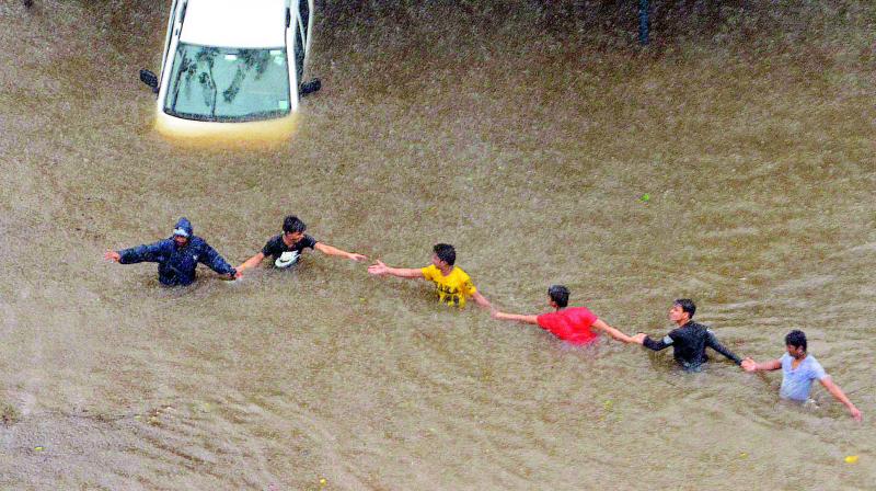 People make their way through a flooded street during heavy rains in Mumbai on Tuesday. (Photo: PTI)