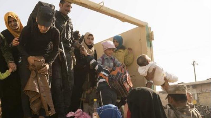 Iraqi soldiers help women and children who have fled fighting in Mosul into trucks to take them to camps. (Photo: AP)