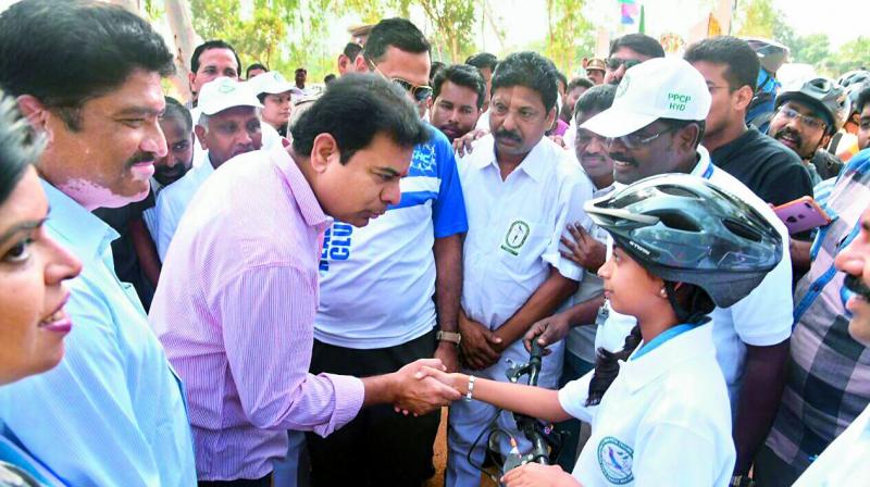 Minister K.T. Rama Rao shakes hands with a cyclist.