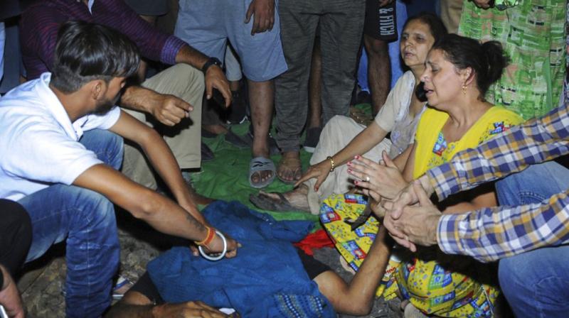 Relatives mourn near a victim at the site of a train accident at Joda Phatak in Amritsar. (Photo: PTI)