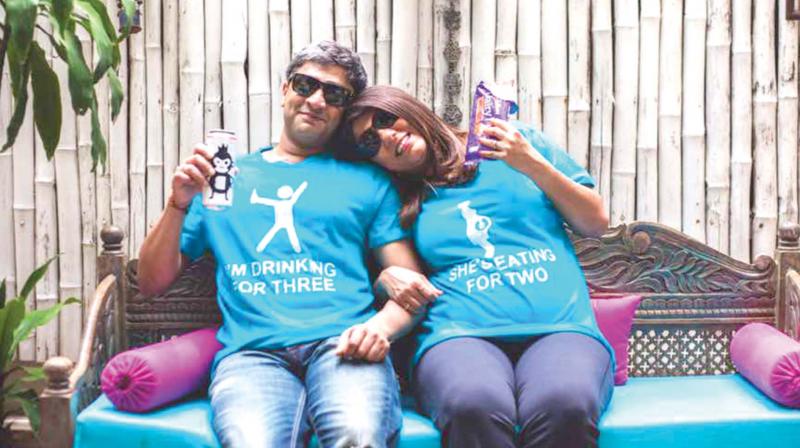 Shwetambari and Rahul pose for a photograph with customised tees as a part of their baby shower.