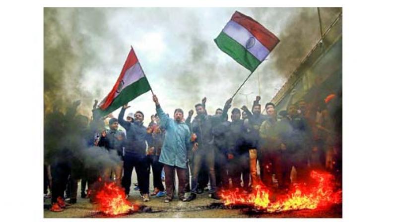 Protestors raise slogans and burn tyres during a demonstration against the Pulwama terror attack, in Jammu.
