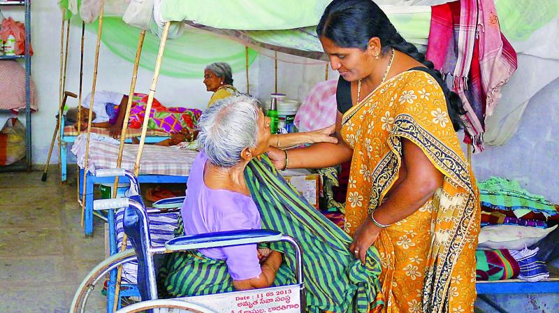 Yakub Bee helps dress a handicapped elderly lady, resident at the Sahrudaya old age home on Monday. (Photo: DC)