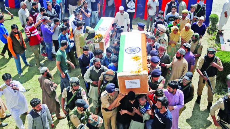 Police officers and family members carry coffins of police officers who were killed by rebels, during a wreath laying ceremony at a base camp at Shopian. (Photo: AP)