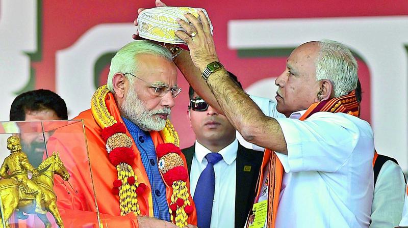 Prime Minister Narendra Modi being presented a Mysore Peta by state president B. S. Yeddyurappa during in Bengaluru on Sunday. (Photo: PTI)