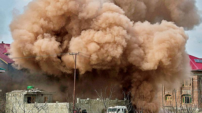 Smoke billowing from the house targeted by the securitymen for eliminating a militant during an encounter at a village in Budgam district on Tuesday.