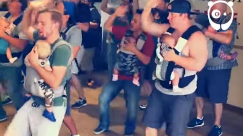 A video of one such session shows the dads clearly having a good time grooving to the music while carrying their children in baby-carrying pouches. (Credit: YouTube)