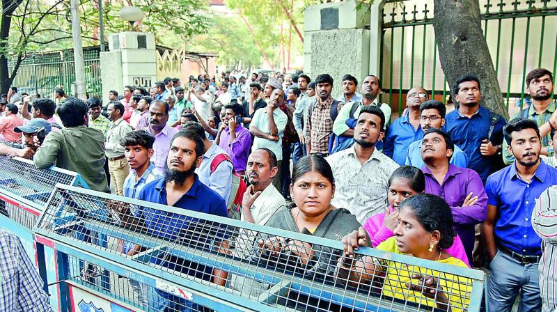 A shocked crowd looks at the Khan Lateef Khan Estate building as some firefighters try to douse the fire on Wednesday.