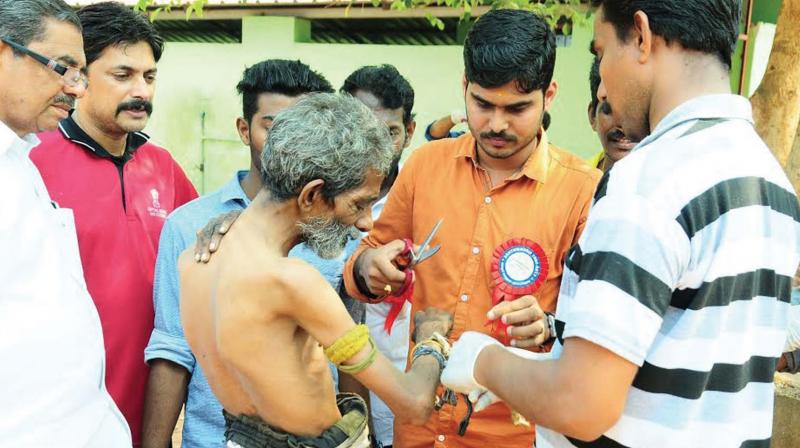 Volunteers help an elderly man to clean up at Tali Zamorins Higher Secondary School after finding him wandering on the street.