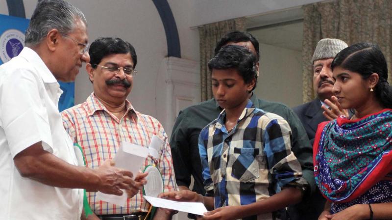 Chief Minister Pinarayi Vijayan distributing  financial aid to children who lost their parents at Puttingal fire work tragedy. (Photo: DC)