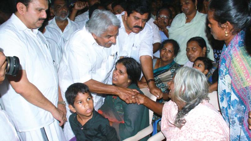 Former chief minister Ommen Chandy listens to women at the relief camp during the UDF teams visit  at Poonthura on Monday. MLAs K. Muraleedharan and V. S. Sivakumar are also seen. 	(Photo: DC)